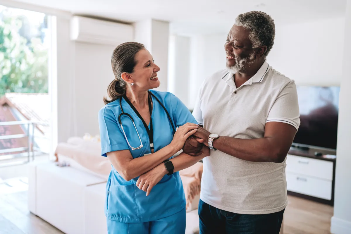 A Mily's caregiver helping a client walk, arm in arm, both smiling.